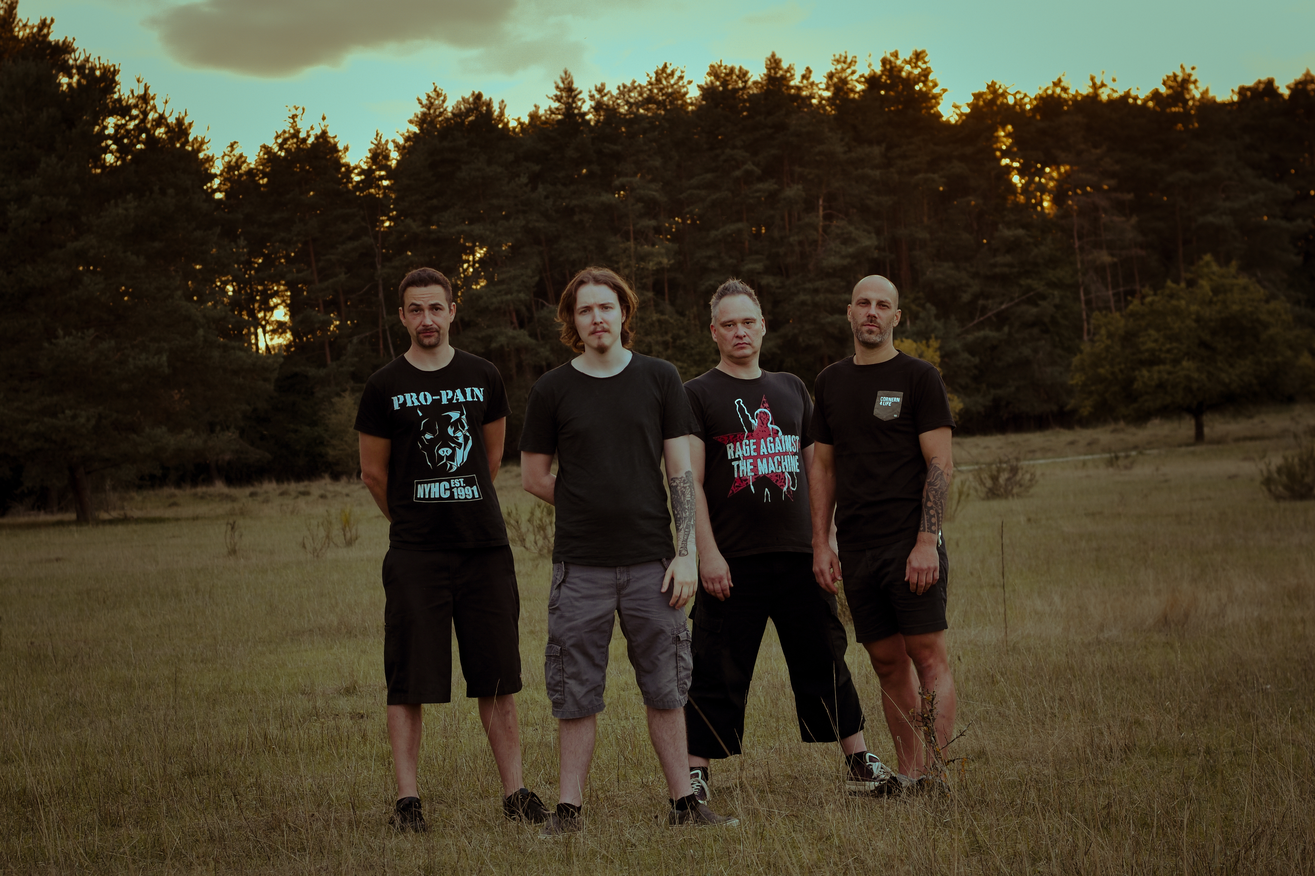 Karmament - The Band on a field in front of a forest with a slightly tilted camera angle